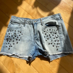 Jeansshorts med nitar - Snygga ljusblå jeansshorts med coola nitar på framsidan. Perfekta för sommardagar!