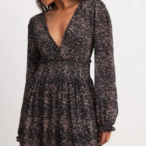 Svart och beige klänning med v-ringning - Snygg svart och beige klänning med v-ringning och långa ärmar. Slutsåld på Na-Kd inköpt för 499 förra sommaren aldrig använd. 