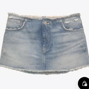 Blå jeanskjol - Snygg blå jeanskjol med slitna detaljer och fransig kant. Kjolen har en klassisk femficksdesign och stängs med knapp och dragkedja framtill. Perfekt för en avslappnad stil.