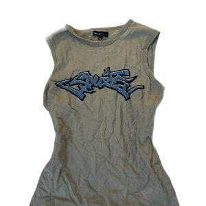 Grön ärmlös topp med graffiti-tryck - Snygg grön ärmlös topp från Missguided med ett coolt graffiti-tryck i blått och svart på framsidan. Perfekt för en avslappnad stil. Är i XL men passar mig som har S