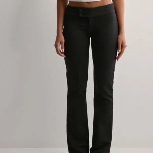 Svarta bootcut byxor - Snygga svarta bootcut byxor med låg midja och två knappar framtill. Från nelly endast använda en gång