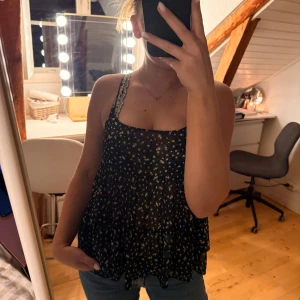 2 blommiga linnetoppar från H&M Divided - Säljer två söta linnetoppar från H&M Divided i storlek 34. Ena toppen är svart med små blommor i vitt och gult, den andra är grön med vitt blommönster. Båda har tunna axelband och flowig passform, perfekta för varma dagar. Materialet är lätt och luftigt. 70kr för båda, 40kr styck. 