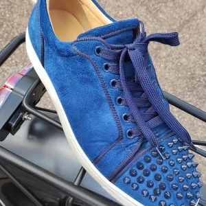 Inte till salu men säg hur mycket ni skulle betala  - Snygga blå sneakers i mocka från Louboutin med ikonisk röd sula och coola nitar framtill. Skorna har snörning, rund tå och vit platt sula. Perfekta för dig som vill sticka ut med exklusiv streetstyle.