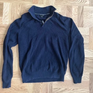 Massimo Dutti Marinblå stickad half zip-tröja  - Snygg marinblå stickad tröja från Morris med half zip-dragkedja och hög krage. Tröjan har lång ärm och ribbade muddar. Perfekt för lager-på-lager och chill stil under höst och vinter.