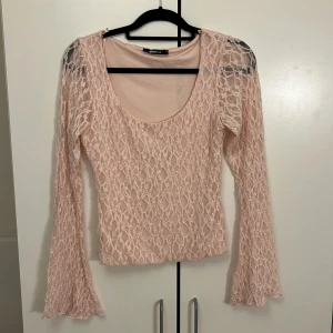 Rosa spetsblus från Gina Tricot - Supersöt ljusrosa blus i spets från Gina Tricot med långärmade utsvängda ärmar och rundad urringning. Helt ny utan prislapp!