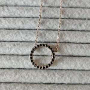 Halsband Edblad - Halsband från Edblad i roseguld med svarta stenar. I mycket fint skick  Diametern på själva smycket med små kubiska zirkona på ena sidan är ca 2,5 cm, tjockleken på ringen ca 6 mm. Längden på kedjan ca 23,5 cm på bägge sidor+låset. Längden går att justera.