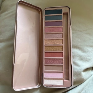 Ögonskuggspalett i metallask - Snygg ögonskuggspalett med 12 olika nyanser i både matta och skimriga färger. Paletten innehåller allt från mörkgrönt och blått till rosa, guld, beige och lila toner.
