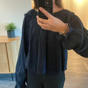 Svart prickig blus från Gina Tricot - Supersöt marinblå blus från Gina Tricot i storlek 158/164. Blusen har ett prickigt mönster, rynkade detaljer och vida, långa ärmar. Den är luftig och har en rund halsringning.