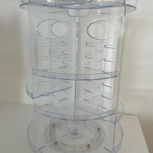 Roterande sminkställ genomskinlig - Säljer ett genomskinligt roterande sminkställ i akrylplast med flera fack och hyllor för smart förvaring av sminkprodukter som borstar, läppstift och ögonskuggor. Perfekt för att hålla ordning på sminkbordet och enkelt hitta dina favoriter. Man kan ändra vart man vill ha de med små gummisnoddar som jag visar på en bild. Den är alltså justerbar och går att ta i bitar. Osäker vart den är köpt ifrån men kommer inte till användning. Kontakta gärna innan köp!