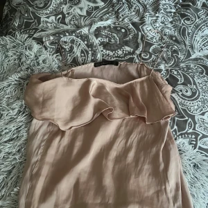 Beige volang topp från Zara Basic - Supersöt beige topp från Zara Basic med tunna axelband och volang upptill. Toppen  har en mjuk, silkeslen känsla och en enkel, elegant look som passar perfekt till sommaren. Säljer då den inte längre kommer till användning!