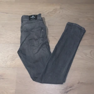 Grå jeans från Replay, modell Wallys - Snygga grå jeans från Replay, modell Wallys. Jeansen har klassisk femficksdesign, raka ben och diskreta slitningar för en cool look. Materialet är mjukt och stretchigt jeans, perfekt för dig som gillar bekväma och stilrena byxor. Väldigt bra skick det finns inga tecken på användning. Men ingen prislapp kvar. Köpta från kidsbrandstore för 799kr. Pris kan diskuteras vid snabb affär🚚 