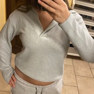 Ljusgrå ribbad stickad tröja - Säljer en ljusgrå stickad tröja med ribbad struktur och v-ringad krage!! Passar till nästan vad som helst och är jätte mysig att ha på sig hemma!🌸