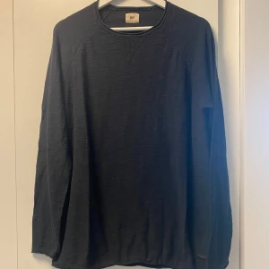 Svart långärmad tröja från Lee - Svart långärmad tröja från Lee med rund hals och diskret ribbad detalj vid halsringningen. Tröjan är enkel och har en loose passform, perfekt för chill dagar. Materialet känns mjukt och är troligtvis bomull. Snygg att matcha med jeans eller joggers.