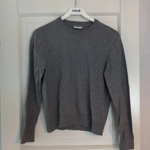 Grå stickad tröja med rund hals Grunt - En grå stickad tröja med rund halsringning och långa ärmar från Grunt. Ribbstickade muddar vid ärmslut och nederkant. Barn strl L