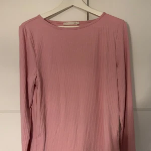 Rosa ribbad långärmad tröja - Säljer en ljusrosa långärmad tröja. Tröjan är ribbad och har en enkel, rund halsringning. Perfekt att styla med jeans eller kjol för en chill look. Materialet är mjukt och skönt bomullstyg.