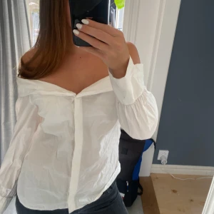 Vit offshoulder skjorta från Zara - Säljer en vit offshoulder skjorta från Zara i storlek S. Skjortan har långa ärmar och knappar framtill