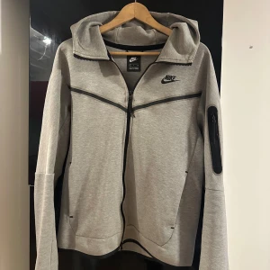 Grå Nike Tech hoodie med dragkedja - Grå Nike Tech Fleece i storleken S, tröjan är inte använd så mycket och säljs pga den ej passar min stil längre.