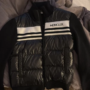 Svart moncler cardigan jacka  - Svart moncler jacka direkt köpt från moncler butiken i London. Finns även påse till den! 14-15 i storlek o passar även dig som är 164-170cm lång köpte den för 6500kr