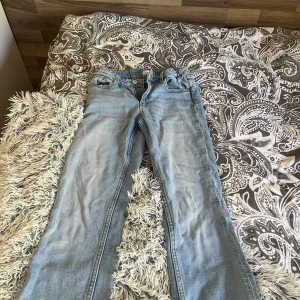 Ljusblå jeans från Gina Tricot - Säljer ett par ljusblå jeans från Gina Tricot i storlek 152/xxs. Klassisk femficksmodell med raka ben och normal passform. Jeansen har snygga slitningar och är tillverkade i mjukt denimtyg med bruna sömmar.