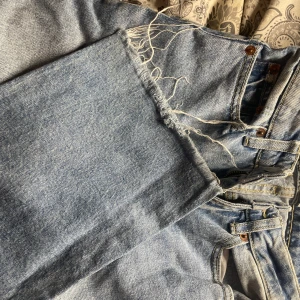 Ljusblå jeans med rå kant från 157 - Säljer ett par ljusblå jeans från 157 med klassisk femficksdesign och rå, fransig kant vid benslutet. Jeansen har hög midja och raka ben, tillverkade i slitstarkt denim. Perfekta för dig som gillar en chill och trendig look.