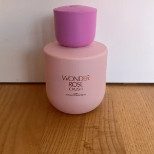 Zara Wonder Rose Crush parfym - Säljer en söt parfym från Zara, Wonder Rose Crush, med en matt ljusrosa flaska och lila lock. Flaskan har en rundad form och guldig text framtill. Perfekt för dig som gillar fräscha och blommiga dofter.