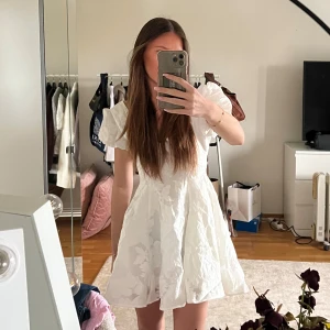 Vit klänning med puffärmar - Säljer en söt vit klänning med puffärmar och v-ringning. Klänningen har ett blommigt mönster och är perfekt för sommarens alla tillfällen och bla för student.🤍Ej använd, endast provad. Nypris 1100kr.