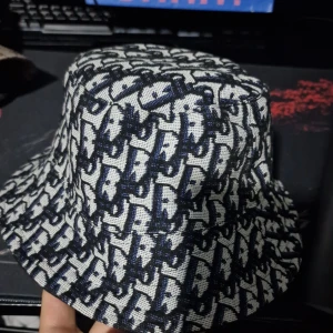 Mönstrad bucket hat från Off Work - Snygg bucket hat från Off Work med ett unikt mönster i svart och vitt. Perfekt för att ge din outfit en cool touch. Hatten har en klassisk form och är tillverkad i ett bekvämt material.