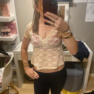 Beige spetsblus - Säljer en söt beige spetsblus med v-ringning och korta ärmar. Blusen är croppad och har ett romantiskt utseende som passar perfekt för sommarens varma dagar. Perfekt för att ge en feminin touch till din outfit.