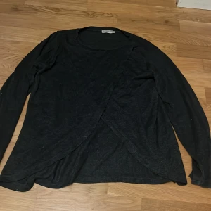 Mörkgrå omlottopp från Angelology - Säljer en mörk grå omlottopp från Angelology i storlek M. Toppen har långa ärmar och en stilren omlottdesign framtill. Perfekt för en chic och avslappnad look. 🖤