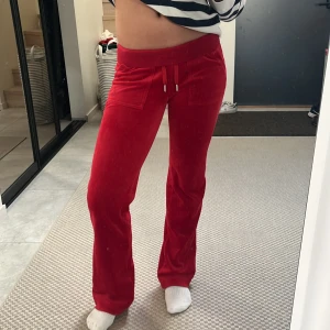 Röda mjukisbyxor från Juicy Couture - Snygga röda mjukisbyxor från Juicy Couture med dragsko i midjan och fickor fram. Perfekta för en avslappnad stil med en touch av lyx. Byxorna har en bekväm passform och är tillverkade i mjukt material. Jag är 163 lång och de passar perfekt. Knappt använda. Ordinarie pris var 1200kr.