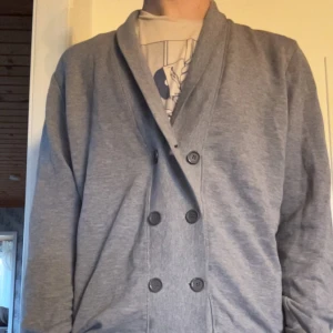 Grå Cardigan Med dubbelknäppning  - Säljer en stilren grå kofta med dubbelknäppning. Storlek M och skick 9/10. 