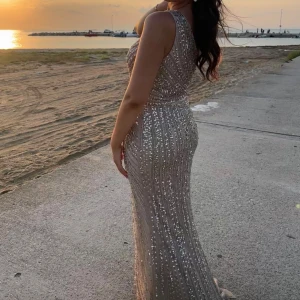 Glittrig champagnefärgad långklänning - Säljer en fantastisk glittrig långklänning i champagnefärg. Klänningen har en elegant oneshoulder-design och en slits som ger en extra touch av glamour. Perfekt för speciella tillfällen! Storlek 36. Använd vid ett tillfälle. Köpt på Dressroomlinne för 2600kr. För referens: längd 171 cm, bär vanligtvis 36/38 i kläder.