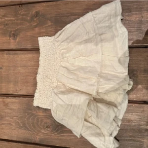 Vit volangkjol - Charmig vit kjol med volanger och elastisk midja. Perfekt för en somrig look med sin luftiga design och korta längd. Tillverkad i ett lätt material som ger en skön känsla.