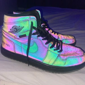 Reflekterande Nike Air Jordans - Säljer ett par unika reflekterande Nike Air Jordans med svart snörning. Skorna har en cool, skimrande yta som ändrar färg beroende på ljuset. Perfekta för att sticka ut i mängden!