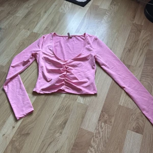 Rosa långärmad topp från NLY Trend - Säljer en söt rosa långärmad topp från NLY Trend. Toppen har en v-ringning och snygg scrunchdetalj framtill som ger en fin passform. Perfekt för att liva upp garderoben! 💖