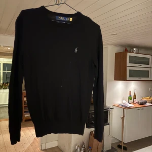 Svart tröja från Ralph Lauren - Säljer en stilren svart tröja från Ralph Lauren i merinoull. Tröjan har en klassisk design med rund hals och en liten broderad logotyp på bröstet. Perfekt för en elegant och bekväm look.  Köpt för 2500kr på Ralph laurens shop och är i otroligt bra skick. Passar dig som är mellan 165-175 och är otroligt snygg. Hör av er vid eventuella frågor!!!!!