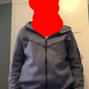 Blå hoodie från Nike - Säljer en blå hoodie från Nike med dragkedja och huva. Perfekt för en avslappnad stil. Den har långa ärmar och en bekväm passform.
