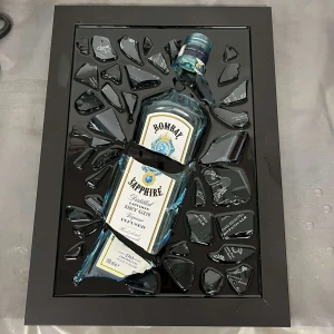 Bombay Saphire Gin Tavla - Unikt konstverk med en Bombay Sapphire-flaska inramad i svart. Flaskan är omgiven av krossade glasbitar och är handgjord av Epoxycreations. Obs kommer inte vara exakt som på bild eftersom varje verk blir unikt🤩