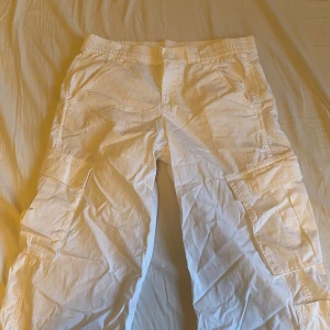 Vita cargobyxor från H&M Divided - Säljer ett par vita cargobyxor från H&M Divided. Byxorna har flera praktiska fickor och en elastisk midja för extra komfort. Perfekta för sommaren då dem har liknande material till linnebyxor!💕☀️