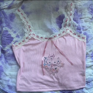 Kawaii cami topp - Så gulligt linne med spets och tryck med katter och blommor och en liten rosett! 💕💕💕Köpt second hand men superfint skick. Misstänker den är från typ shein eller liknande då jag är väldigt picky med material och den här har mer ett ”syntetiskt” material vilket jag inte tycker är skönt att ha på mig. Har inga bilder hur den ser ut på då den ej passar mig men passar en Xs-S. Lite croppad modell. 🥰