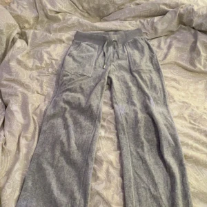 Grå mjukisbyxor med snörning - Säljer ett par grå mjukisbyxor med bekväm passform och snörning i midjan. Byxorna har praktiska fickor både fram och bak, vilket gör dem perfekta för en avslappnad stil. Materialet är mjukt och skönt, idealiskt för mysiga dagar hemma. Och på sista bilden så har en liten deltalj gått av från snöret men inget som märks.