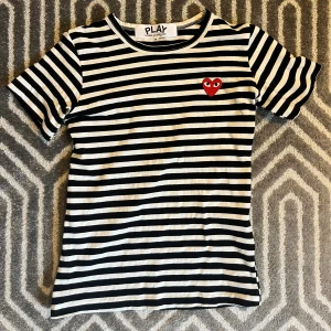 Randig t-shirt Comme des Garçons Play - Säljer en snygg svartvit randig t-shirt från Comme des Garçons Play i storlek S med det klassiska röda hjärtat på bröstet. En liten defekt på ryggen(se sista bilden) som knappt syns när man har på den. Tveka inte att skriva ifall du undrar nåt!✨