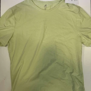 Ljusgrön t-shirt från H&M - Fräsch ljusgrön t-shirt från H&M i slim fit-modell. Enkel och stilren design utan mönster, med rund hals och korta ärmar. Perfekt för dig som gillar minimalistisk stil och mjuka färger.