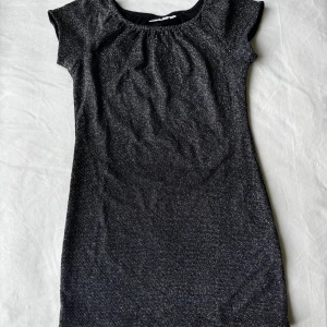 Glittrig klänning  - Glittrig klänning från Kappahl i storlek 146. Klänningen har rund halsringning & korta ärmar. Fraktar inom 24h!