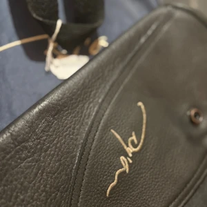  Dy'on  Chaps i storlek xs som nästan aldrig är använda, säljer för 900kr - Snygg svart datorväska från Dy'on med guldfärgad logga. Väskan är tillverkad i äkta skinn och har en praktisk dragkedja samt handtag. Perfekt för att bära din laptop och andra viktiga grejer med stil.