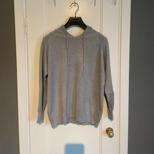 Grå merinoull hoodie  - En stilren grå hoodie med huva och snörning. Tröjan är långärmad och har en mjuk, strechig känsla i materialet. Perfekt för en chill och avslappnad look. 