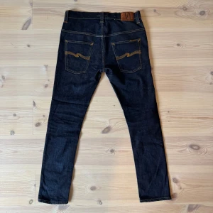 Nudie jeans - Ett par Nudie jeans i modellen Tape Ted. De är i fint skick och i storlek W32 L32, men sitter mer som en W30 L32 i min mening. Hör gärna av er vid frågor och funderingar!🤗