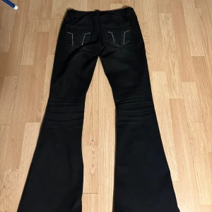 Svarta bootcut jeans med detaljer - Svarta jeans från Gina trocot med bootcut-modell och snygga detaljer på bakfickorna. Jeansen har klassisk femficksdesign, low waist och skön passform. I jättefint skick i storlek S 
