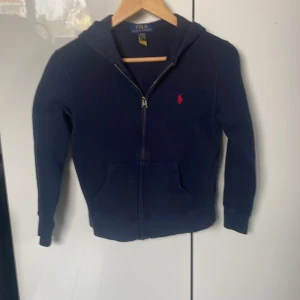 Marinblå hoodie från Polo Ralph Lauren - Snygg marinblå hoodie från Polo Ralph Lauren med dragkedja och huva. I bra skick 
