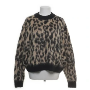 Other stories tröja - Säljer en fluffig stickad tröja med leopardmönster i beige och svart. Tröjan har rund hals, ribbade muddar och lång ärm. Perfekt för dig som vill sticka ut med ett djuriskt mönster och samtidigt hålla dig varm.